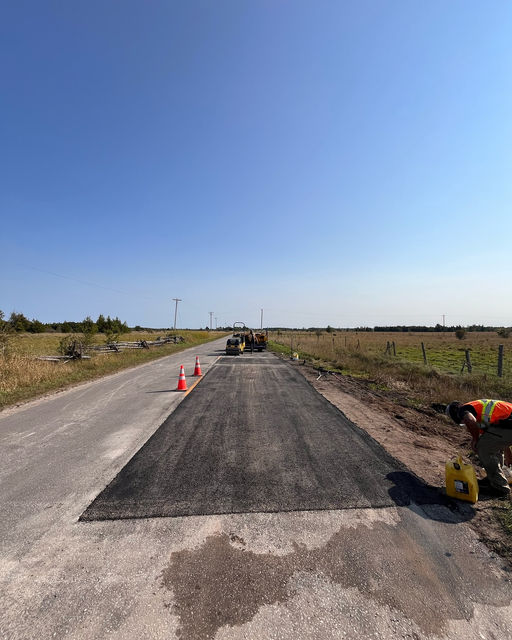 Crew laying fresh hot asphalt on a rural road